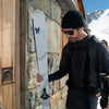 Man leaning Faction Agent 1 white skis against a wall