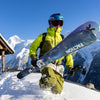 Sam Anthamatten carrying Faction Studio 4 skis in deep snow surrounded by striking mountains.